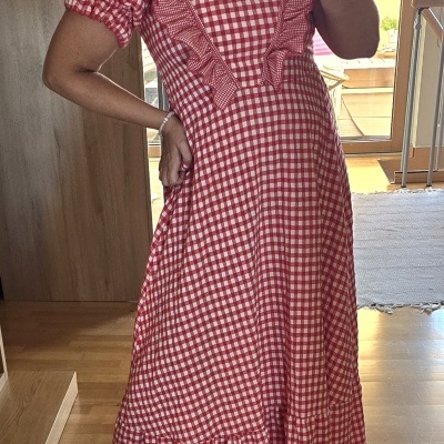 Vestido comprido xadrez vermelho e branco com folhos e mangas curtas bufantes em ambiente interior