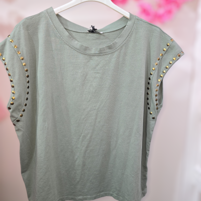 T-shirt verde-acinzentado com rebites dourados nas mangas pendurada em cabide branco