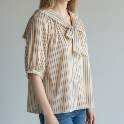 Mulher com blusa listrada bege e azul com gola laço e calças de ganga azul claro