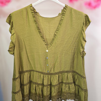 Blusa feminina verde com folhos e renda pendurada em cabide branco