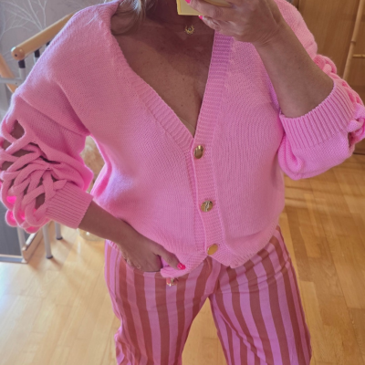 Cardigã rosa malha com botões dourados e calças riscas verticais rosa e vermelho