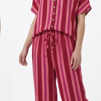Conjunto feminino riscado em tons de vermelho, rosa e púrpura com camisa e calças largas.