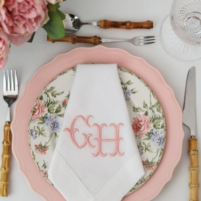 Louça rosa e floral com guardanapo branco bordado GH e talheres com cabo de bambu