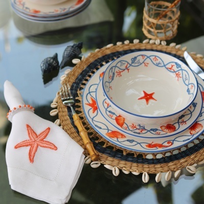 Conjunto de loiça e guardanapo com decoração marinha, base trançada com búzios