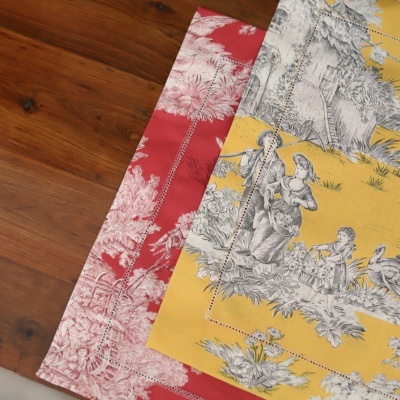 Tecidos estampados vermelho e amarelo com motivos clássicos em cima de madeira