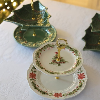 Suporte de porcelana de Natal com dois pratos decorados e alça dourada, sobre toalha branca