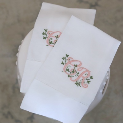 Lenços brancos bordados com letras entrelaçadas CR em rosa e verde.