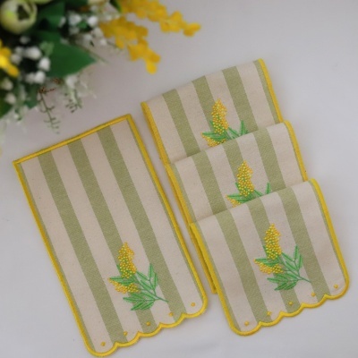Toalhas listradas com bordas amarelas e bordado floral em fundo branco e flores ao lado