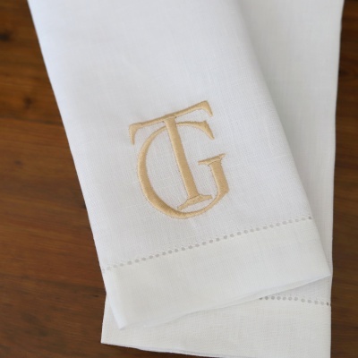Guardanapo branco com monograma TG bordado bege sobre madeira