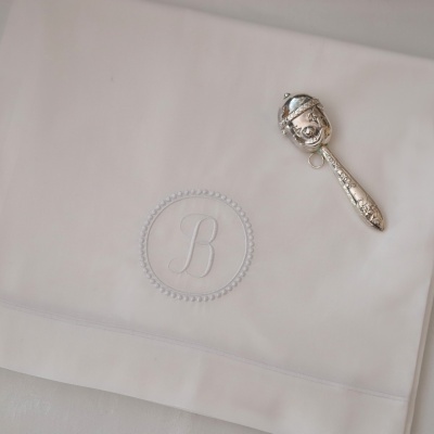Toalha branca com bordado da letra B e colher prateada decorativa