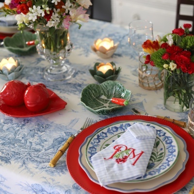 Mesa posta com pratos decorados, guardanapo bordado e arranjos de flores