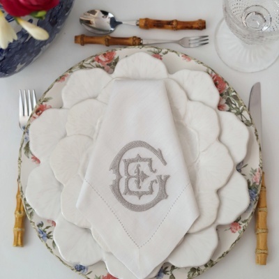 Conjunto de pratos de cerâmica branca e floral com talheres de cabo de bambu e guardanapo bordado