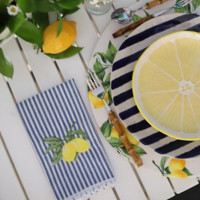 Mesa posta com pratos decorativos e toalha azul de riscas com limões