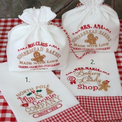 Sacolas e panos de cozinha brancos com estampas natalinas e figuras de biscoitos de gengibre sobre toalha xadrez vermelha