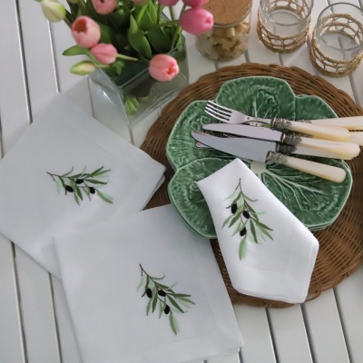 Mesa posta com toalhas, guardanapos, talheres, pratos verdes em forma de folha, copos e vaso com tulipas rosas