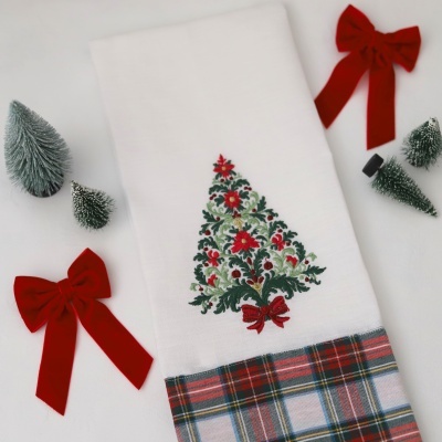 Toalha branca com árvore de Natal bordada e padrão xadrez com decoração natalícia.