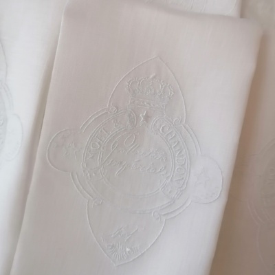 Pano branco com bordado em relevo de símbolo com coroa