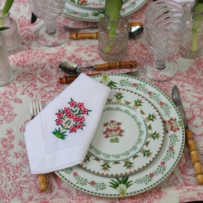 Conjunto de louça floral com talheres de bambu e guardanapo bordado sobre toalha estampada