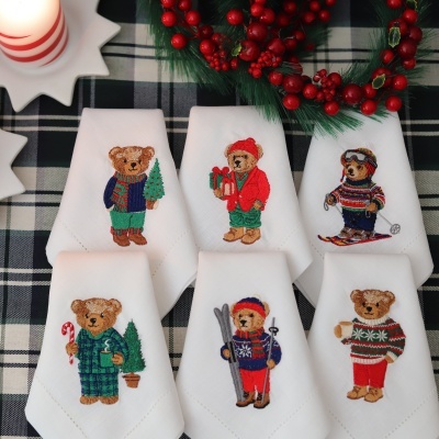 Guardanapos brancos com bordado de ursos vestidos para o inverno em mesa decorada para Natal