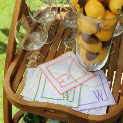 Carrinho de madeira com copos de vidro, guardanapos bordados e jarra com limões amarelos.