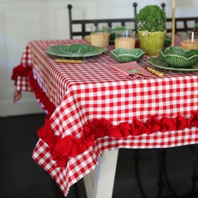 Toalha de mesa xadrez vermelho e branco com pratos verdes em formato de folha e guardanapo na mesa