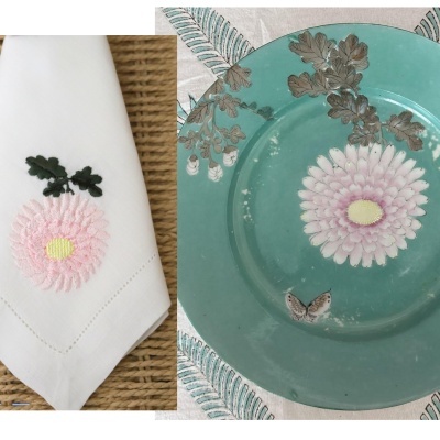 Guardanapo branco bordado e prato azul esverdeado com flor e folhas