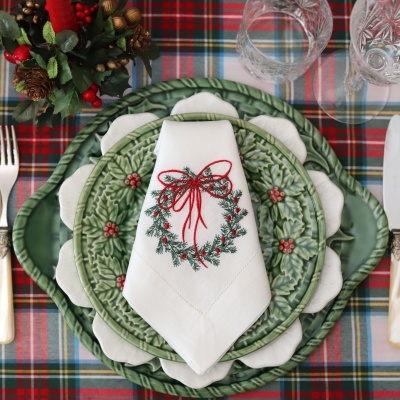 Conjunto de pratos verdes com guardanapo branco bordado com coroa de Natal