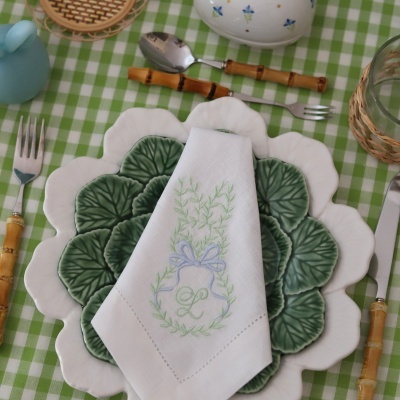 Mesa posta com pratos em forma de folhas, guardanapo bordado, talheres com cabos de bambu.