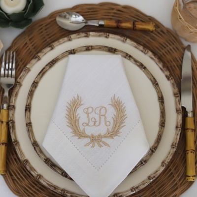 Mesa posta com prato, talheres com cabos de bambu e guardanapo branco bordado