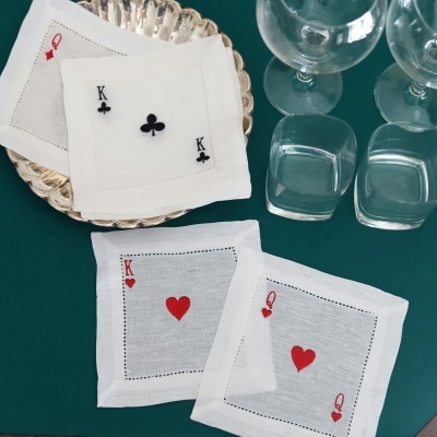 Guardanapos brancos com desenhos de cartas de baralho e copos de vidro