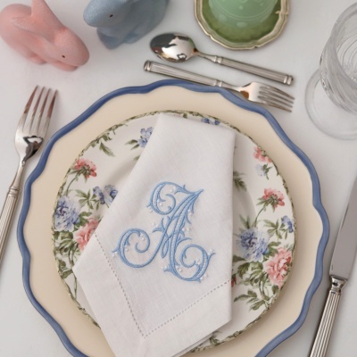 Conjunto de loiça com prato creme e azul, prato floral, guardanapo bordado, talheres e saleiros em forma de coelho