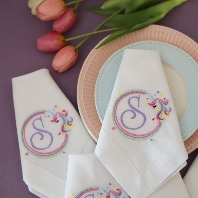 Guardanapos brancos com bordado colorido e pratos pastel juntamente com tulipas