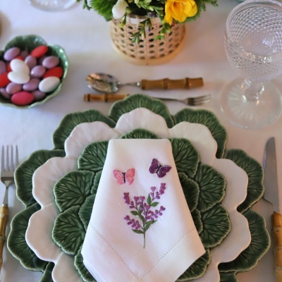 Conjunto de pratos verdes e brancos em forma de folha com guardanapo bordado e talheres de cabo castanho