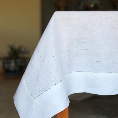 Toalha de mesa branca com linhas perfuradas numa mesa de madeira