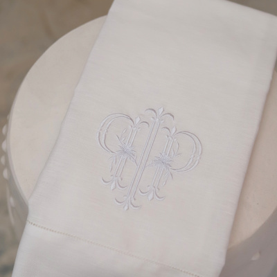 Toalha branca bordada com padrão floral sobre superfície redonda clara
