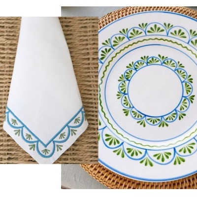 Guardanapo branco bordado e prato cerâmico decorado em azul e verde sobre ráfia