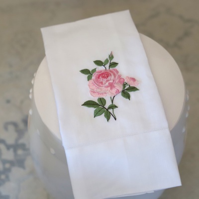 Toalha branca com bordado de rosa cor-de-rosa e folhas verdes
