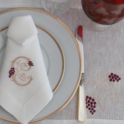 Guardanapo e toalha de mesa brancos com bordado de cachos de uvas cor vinho