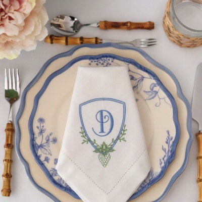 Conjunto de loiça azul e creme com guardanapo bordado e talheres com cabos de bambu