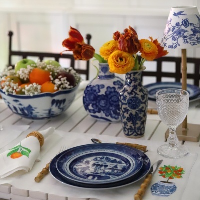 Mesa posta com loiça azul e branca com flores amarelas e guardanapo com padrão de laranjas