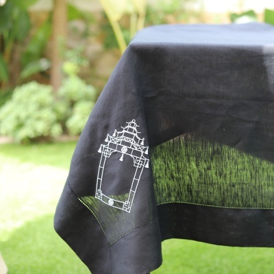 Toalha de mesa preta com bordado branco em ambiente exterior verde