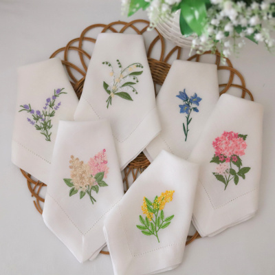 Guardanapos brancos com bordados florais sobre base de rattan