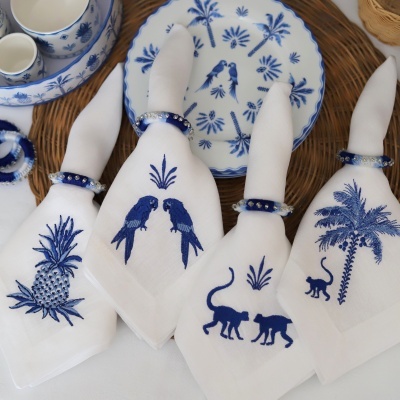 Guardanapos de tecido branco com bordados azuis tropicais e acessórios de mesa em azul e branco