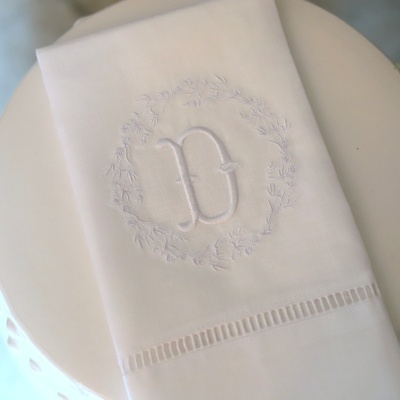 Guardanapo branco bordado com letra D numa superfície branca