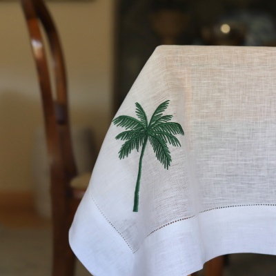 Toalha de mesa branca com bordado de palmeira verde num canto