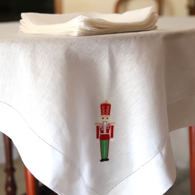 Toalha de mesa branca com bordado de soldado de brinquedo colorido e guardanapos brancos empilhados