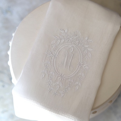Toalha branca com bordado floral e letra M