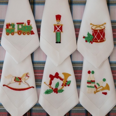 Toalhetes brancas com bordados natalícios coloridos de comboio, soldado, tambor, cavalo de baloiço, corneta e sinos