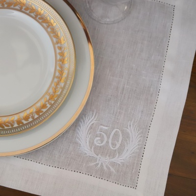 Pratos de porcelana branca com bordas douradas e guardanapo branco bordado