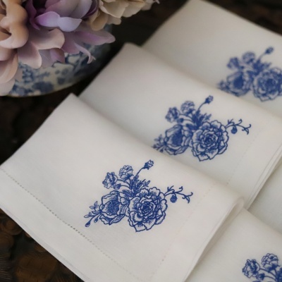 Guardanapos de tecido branco com bordado azul de flores
